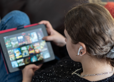 A person on a couch looks at a tablet