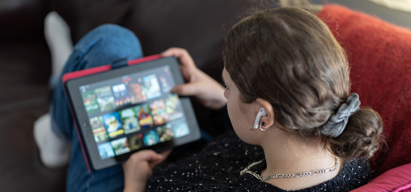 A person on a couch looks at a tablet